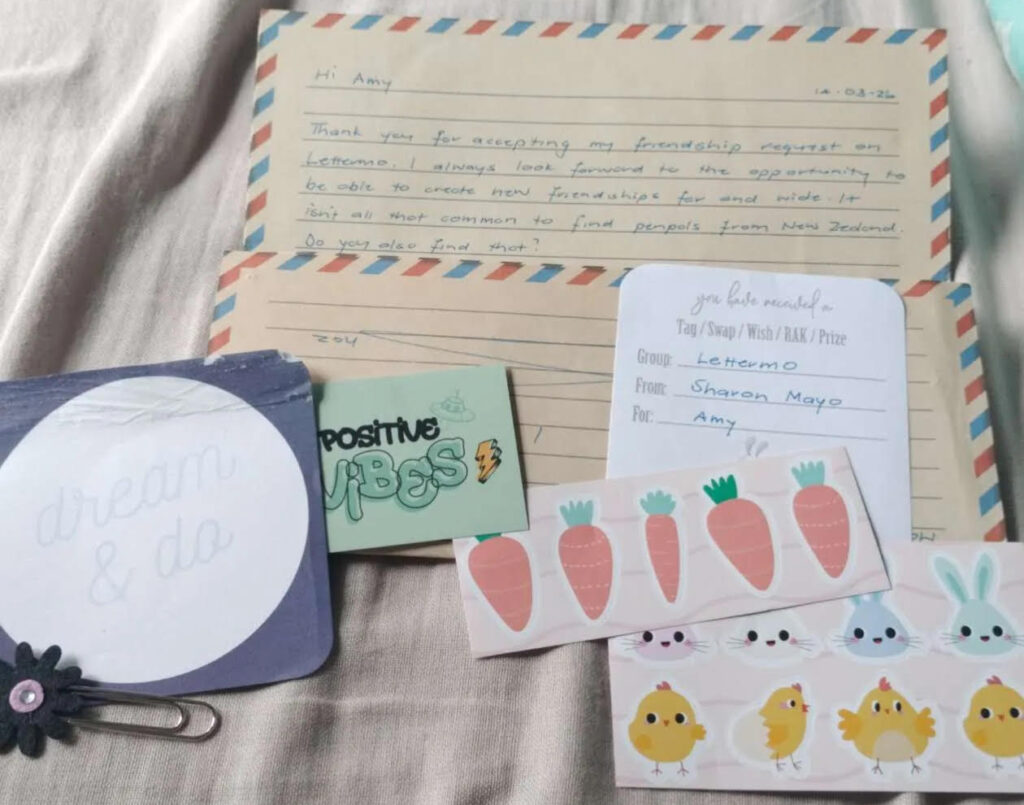 Picture of a letter on airmail stationary, with a coaster, a custom paperclip, and Easter themed stickers