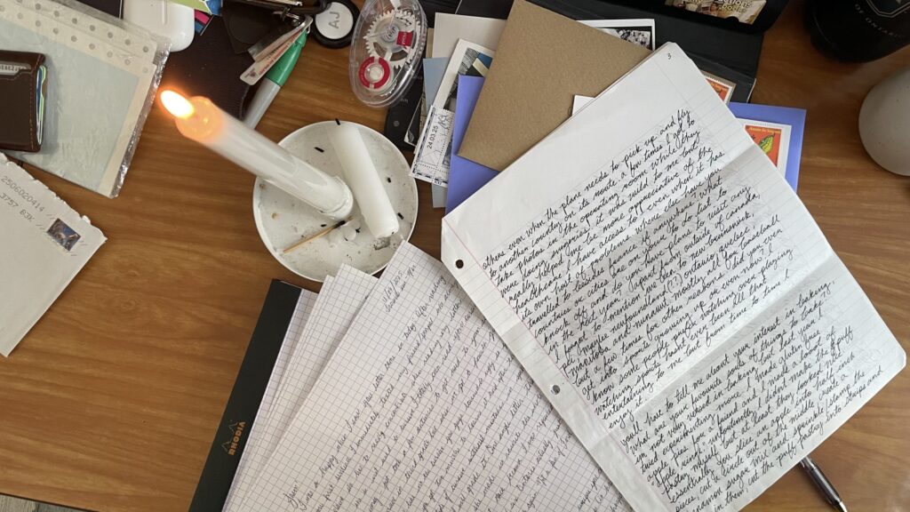 Photo of desk with letter writing supplies, envelopes, and handwritten letters.